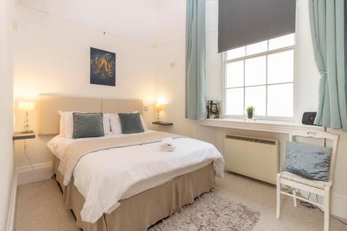 a bedroom with a large bed and a chair at **Sunny and Bright, Thatchers Rock One bed beach front apartment*** in Torquay