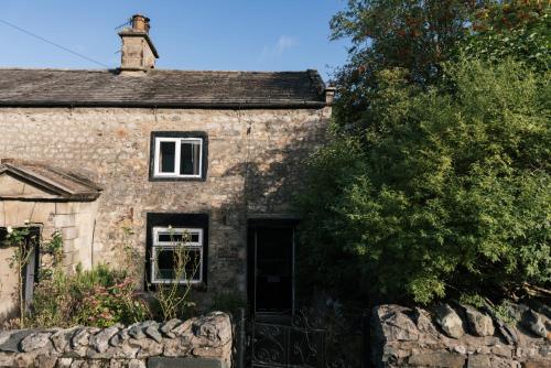 an old stone house with a stone fence in front of it at Our Holiday House Yorkshire, Ingleton - children and doggy friendly in Ingleton