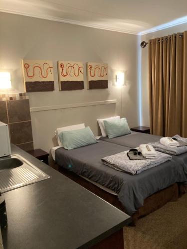 a hotel room with two beds and a sink at Unit 14 A-Block Bains Game Lodge in Bloemfontein