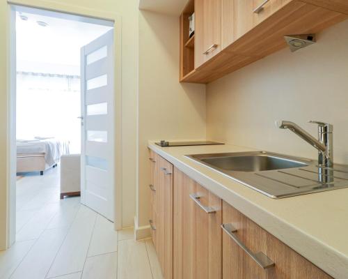 a kitchen with wooden cabinets and a sink at Aquamarina by Baltic Home in Świnoujście