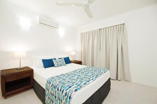 a white bedroom with a bed and a window at Marlin Waters Beachfront Apartments in Palm Cove