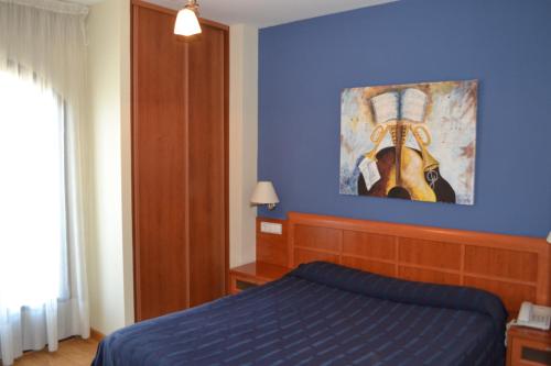 niebieska sypialnia z łóżkiem i obrazem na ścianie w obiekcie Hostal Quevedo w mieście León
