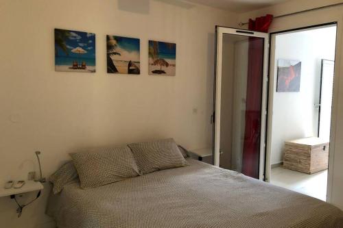 1 dormitorio con 1 cama y algunas fotos en la pared en à deux pas du lagon bel appartement quartier très vivant à l'hermitage, en Saint-Gilles-les-Bains