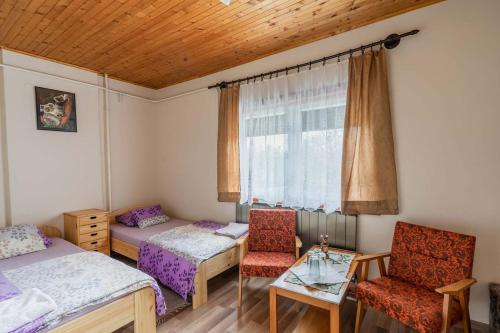 a room with two beds and a table and a window at Gemenc Vendégház in Hercegszántó