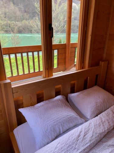 a bed with two pillows in front of a window at Drinska Amazonija, brvanara na obali Drine in Ljubovija
