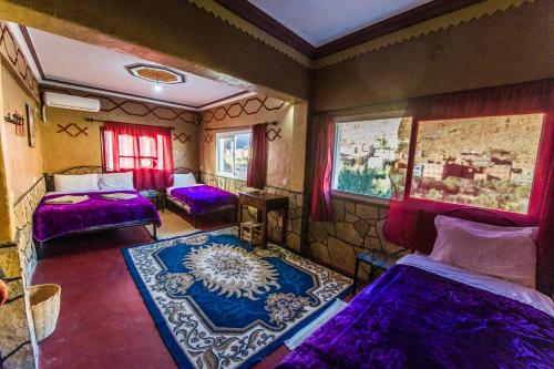 a bedroom with purple beds and a blue rug at Les Jardins De Todgha gorges de todra tinghir in Aït Baha
