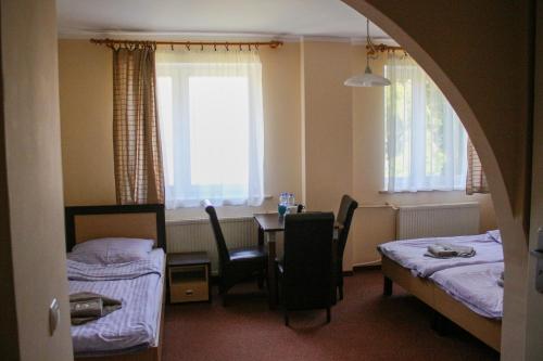 a hotel room with two beds and a table and chairs at Pensjonat 4 Pory roku in Duszniki Zdrój