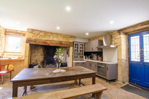 une cuisine avec une table en bois et une cheminée dans l'établissement Chez Rénou et Prospérou maison typique du Sarladait, à Genestal