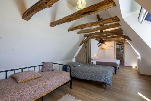 ein Schlafzimmer mit 2 Betten und 2 Stühlen im Dachgeschoss in der Unterkunft Chez Rénou et Prospérou maison typique du Sarladait in Genestal