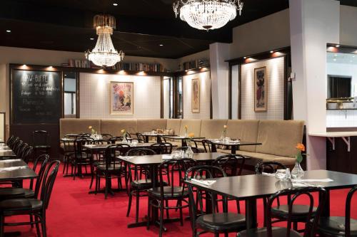 a dining room with tables and chairs and chandeliers at ProfilHotels Savoy in Jönköping