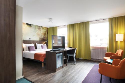 a hotel room with a bed and a desk and chairs at ProfilHotels Savoy in Jönköping