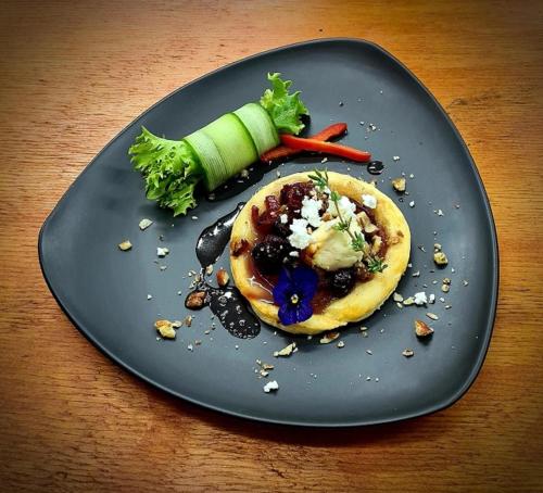 a black plate with food on a wooden table at The Zarafa in Hazyview