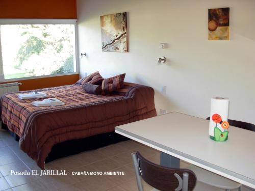a small bedroom with a bed and a table at Posada El Jarillal in Sierra de la Ventana