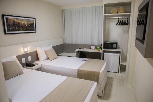 a hotel room with two beds and a desk at Trip Hotel Ubá in Ubá