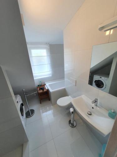 a white bathroom with a sink and a toilet at Good times apartmán in Žilina
