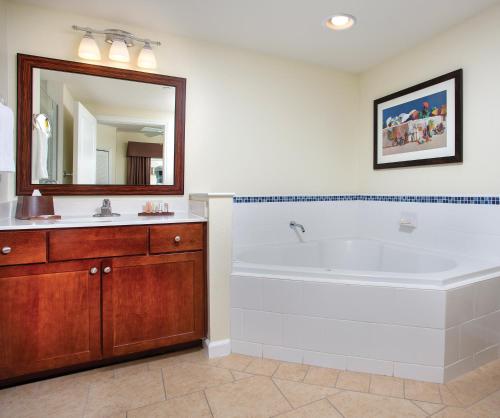 ein Badezimmer mit einer Badewanne, einem Waschbecken und einem Spiegel in der Unterkunft Club Wyndham Oceanside Pier Resort in Oceanside