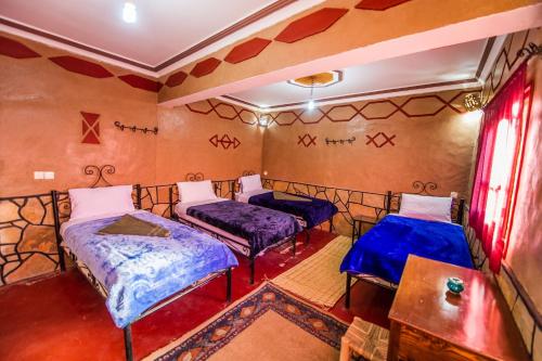 a room with two beds and a table at Les Jardins De Todgha gorges de todra tinghir in Aït Baha