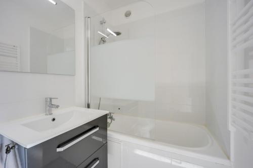 une salle de bain blanche avec un lavabo et une douche dans l'établissement Tribord, à Courseulles-sur-Mer