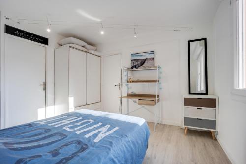 - une chambre avec des murs blancs et un lit avec une couverture bleue dans l'établissement Tribord, à Courseulles-sur-Mer