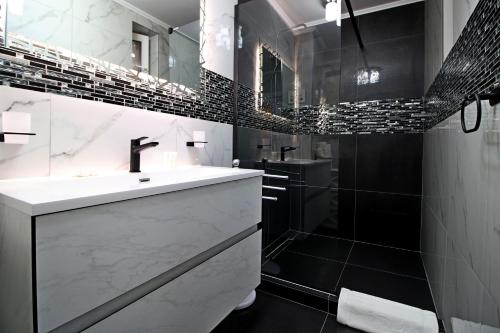 a black and white bathroom with a sink and a shower at White Stone in Sibiu