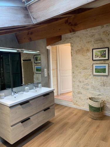 une salle de bain avec un lavabo et un miroir dans l'établissement Chambre Vigne, piscine spa fitness, à Lugon et l’Ile du Carney