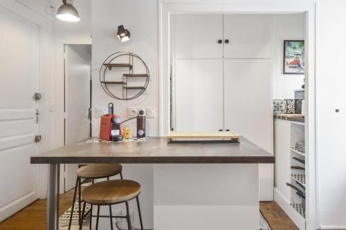 une cuisine avec un comptoir et deux tabourets dans l'établissement Studio Labordette - Welkeys, à Biarritz