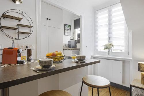 une cuisine avec des murs blancs et un comptoir avec deux tabourets dans l'établissement Studio Labordette - Welkeys, à Biarritz