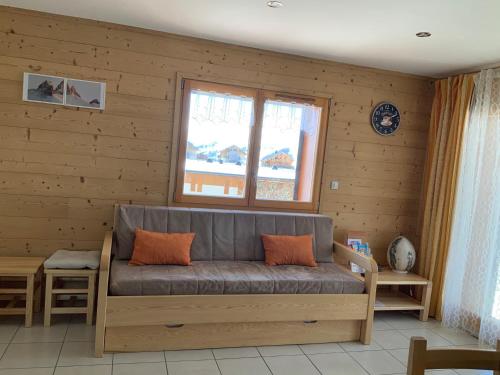 a couch in a room with a wooden wall at Chalet Les Hellebores in La Toussuire