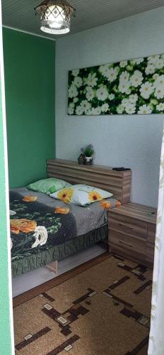 1 dormitorio con cama y pared verde en Olga Guest House, en Cholpon-Ata