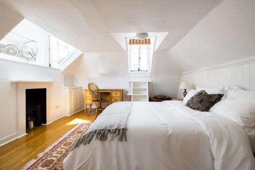 a white bedroom with a bed and a desk at Spacious, Light-Filled 2 Bedroom Apartment in London