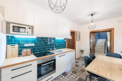 a kitchen with white cabinets and a blue tile wall at Penzion Dubina in Litoměřice