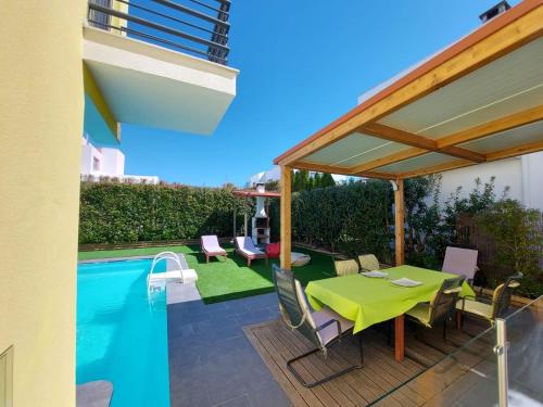 a patio with a green table and chairs next to a pool at Coin de paradis in Quinta do Anjo