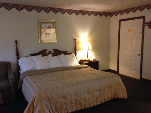 a hotel room with a large bed and a lamp at Fred's Inn Restaurant & Lodging in Norwich