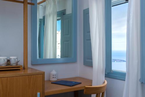 Cette chambre comprend une table avec un miroir et une fenêtre. dans l'établissement Hotel Galini, à Firostefani