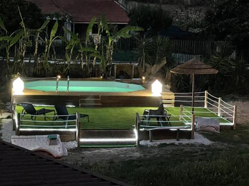 a swimming pool at night with chairs and an umbrella at Quinta da Villa in Cascais
