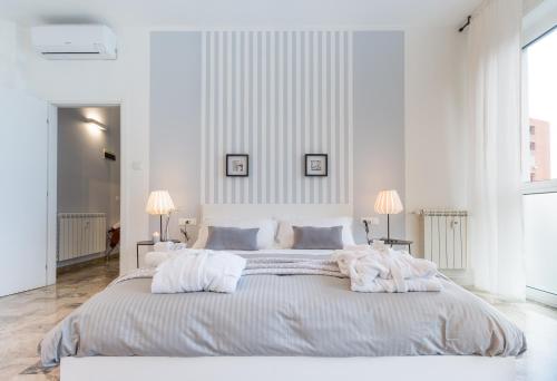 a white bedroom with a large bed with white sheets at 4 Star Bologna Train Station - Self Check-In in Bologna