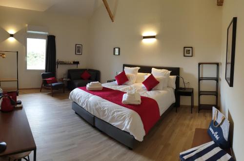 a bedroom with a large bed with red and white pillows at Chambres et Table d'hôtes "La Pastorale Gourmande" FR - NE - EN - DE - IT in Marcollin