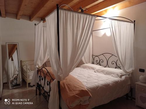 a bedroom with a canopy bed with white curtains at CASA DELLE API in Pisogne