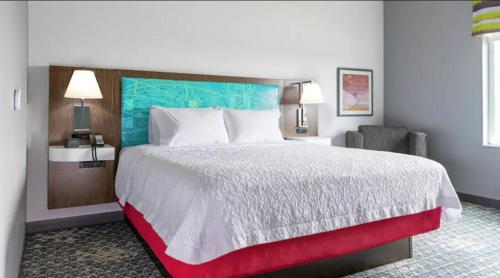 um quarto de hotel com uma cama grande e uma cadeira em Hampton Inn & Suites Ypsilanti, MI em Ypsilanti