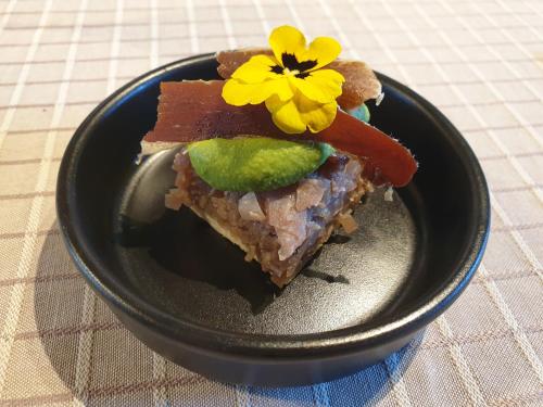 a black bowl with a piece of food with a flower on it at Chambres et Table d'hôtes "La Pastorale Gourmande" FR - NE - EN - DE - IT in Marcollin