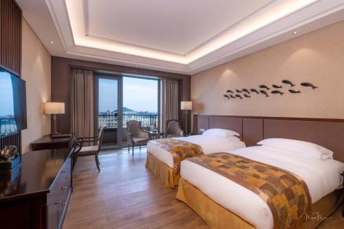 a hotel room with two beds and a large window at Grand Metropark Longxi Conference Center Beijing in Beijing