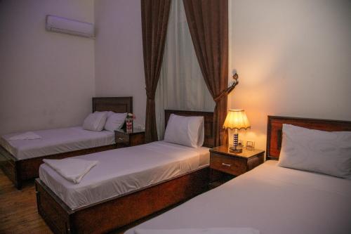 een kamer met twee bedden en een lamp erin bij Regency inn in Caïro
