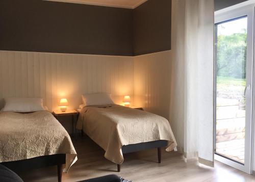 2 camas en una habitación con ventana y 2 lámparas en Lontova puhkemaja, en Kunda
