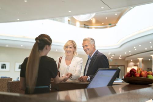 a man and woman shaking hands at a counter at Oberwaid - Das Hotel. in St. Gallen