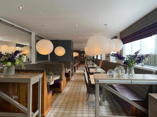 a restaurant with long tables and chairs and lights at The Craigie Hotel in Penicuik