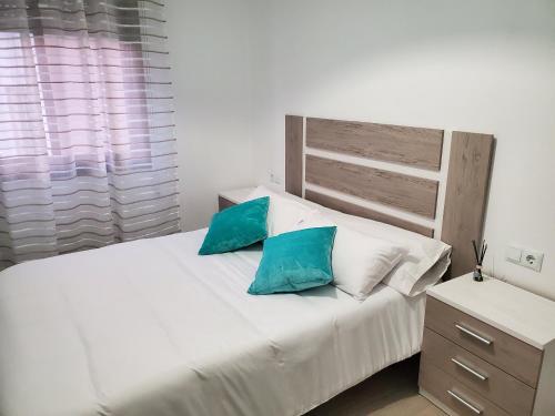 ein Schlafzimmer mit einem weißen Bett mit zwei blauen Kissen in der Unterkunft Piso termal in Ourense