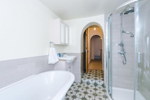 La salle de bains est pourvue d'une baignoire, d'un lavabo et d'une douche. dans l'établissement Churton House, à Chester