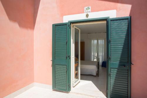 a room with green shutters on a pink wall at Al Ficodindia in Sampieri