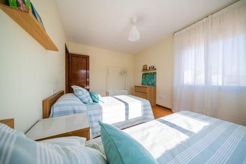 a bedroom with two beds and a window at Apartamento céntrico con vistas al mar in Villanueva de Arosa