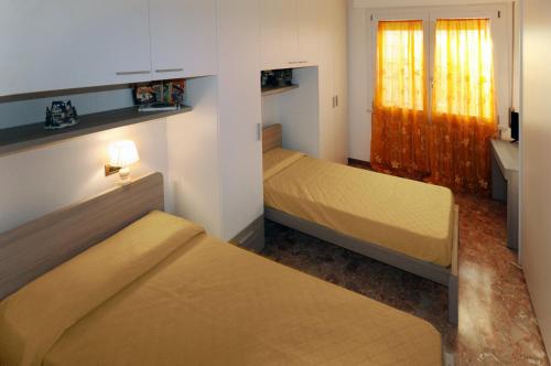 a small room with two beds and a window at Appartamento Del Veig in Cesenatico